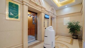 A hotel corridor with a reception area, a plaque on the wall, a television, and a plant. - Vienna International Hotel （Dongguan Hengli Branch） (Dongguan)