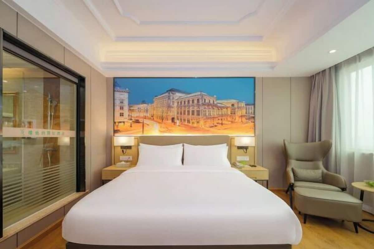 Une chambre d’hôtel avec un grand lit, deux tables de chevet, une chaise et une grande fenêtre.