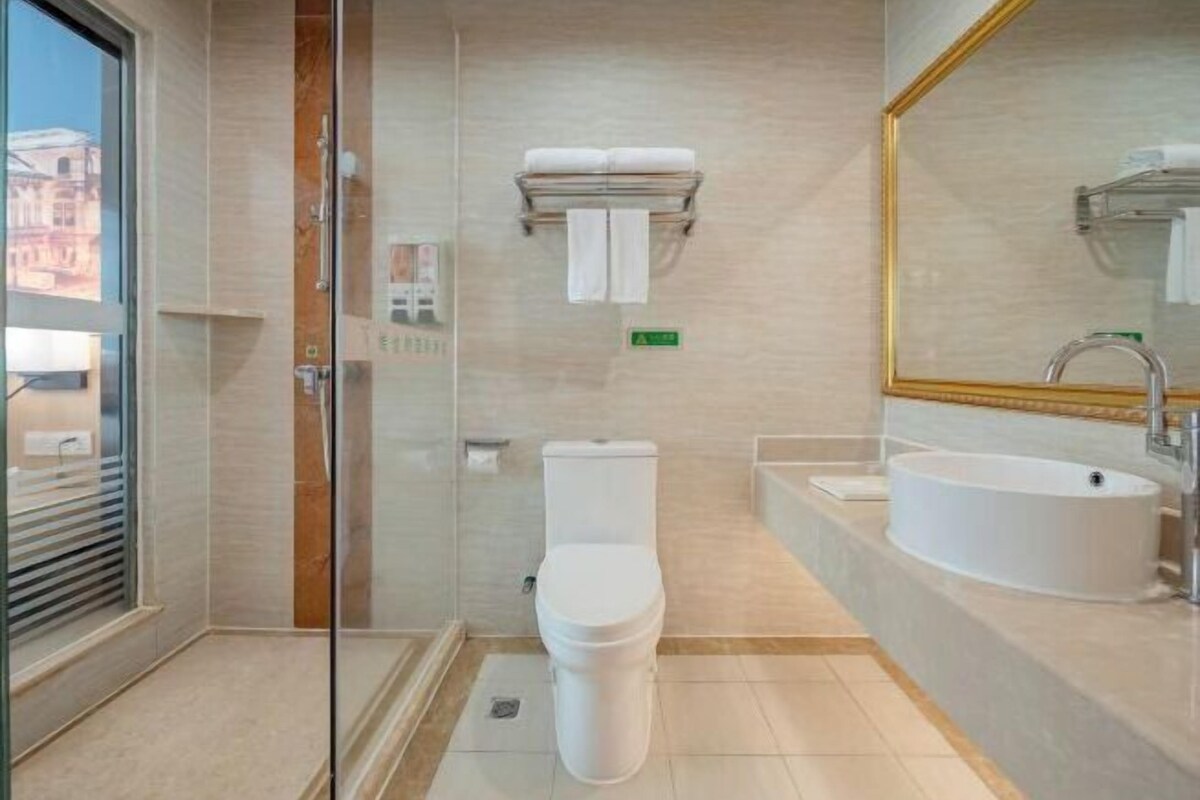 A modern bathroom with a toilet, sink, and glass shower enclosure.
