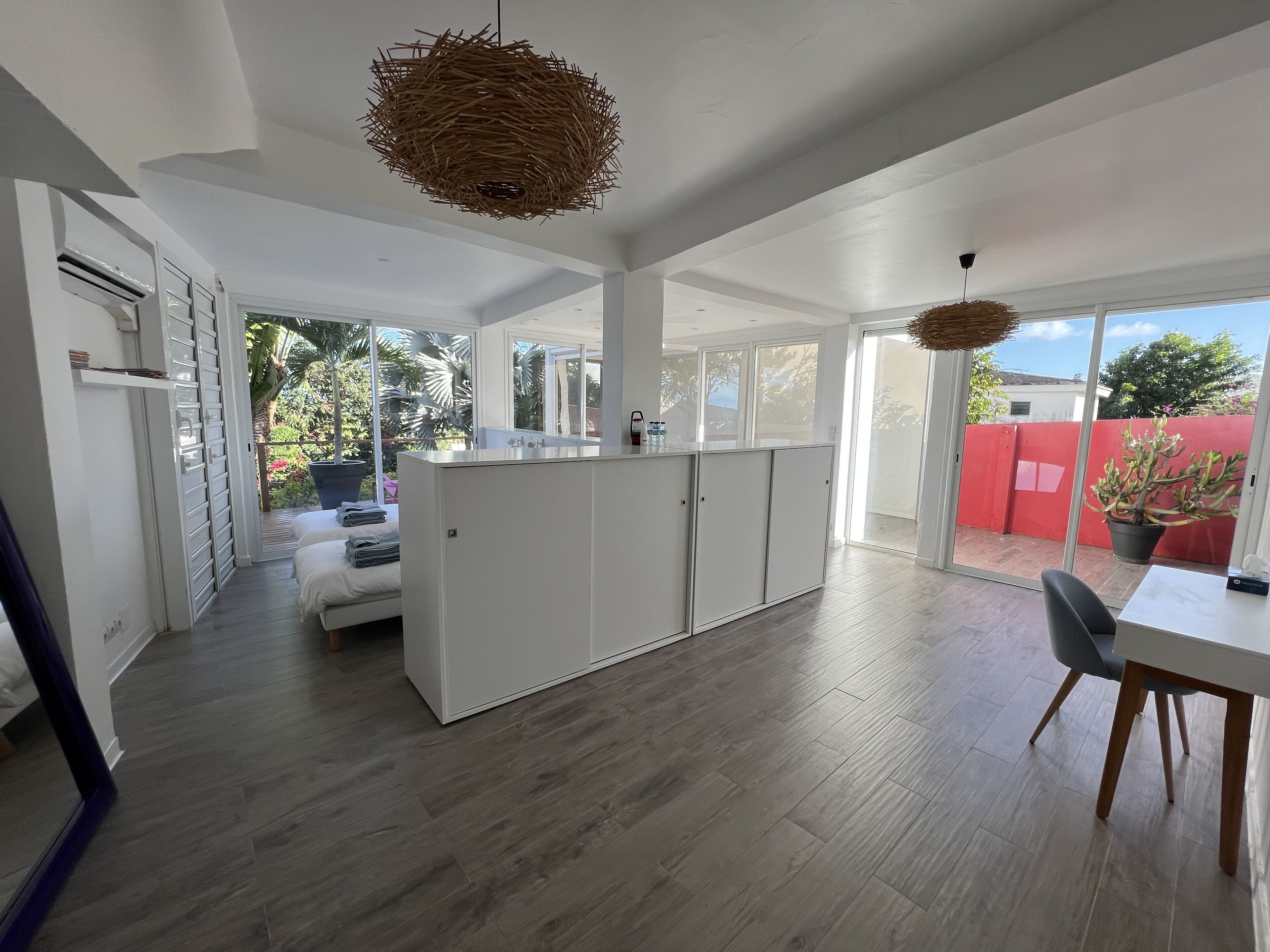 Een moderne keuken met witte kasten, een eethoek met tafel en stoelen, en een groot raam met uitzicht op de omgeving.