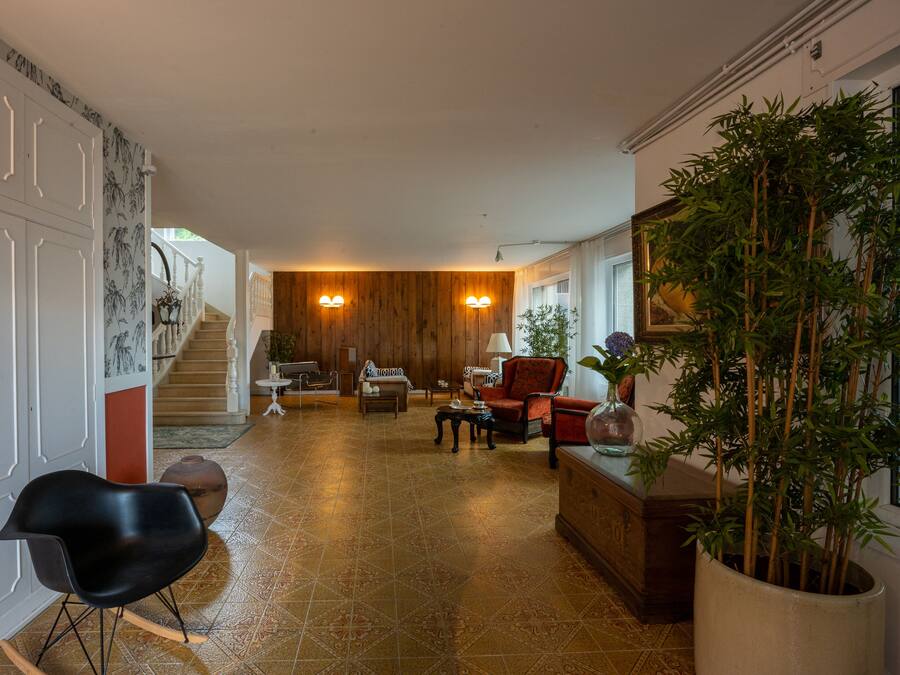 Amplia sala de estar con pared de madera, una escalera y una gran planta en maceta.