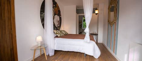 Un dormitorio con cama, mesita de noche, lámpara, un cuadro y un espejo.
