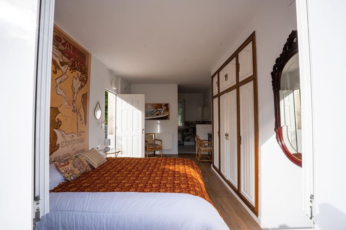 A bedroom with a bed, a wardrobe, and a door leading to another room.