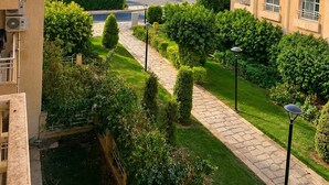 A residential area with modern buildings, a well-maintained garden, and a clear sky. - Casa De Elegant (New Cairo)