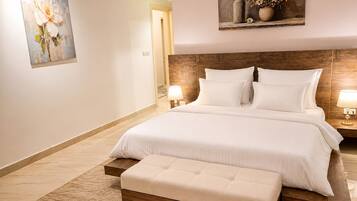 A hotel room with a large bed, a wooden headboard, a bedside table with a lamp, and a painting on the wall.