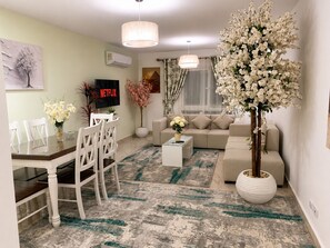 A modern living room with a dining area, a sofa set, and a TV displaying 'NETFLIX'. - Casa De Elegant (New Cairo)