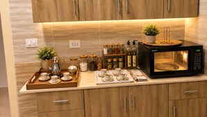 A modern kitchen with wooden cabinets, a microwave, a tray with teacups, and a shelf with jars of spices. - Casa De Elegant (New Cairo)