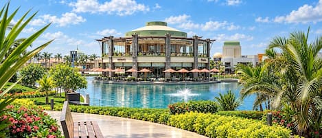 A hotel with a pool, outdoor seating, and a tropical garden.
