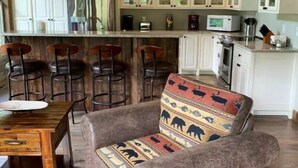 Eine rustikale Küche mit weißen Schränken, Holzbalkendecke und einer Bar mit Hockern.