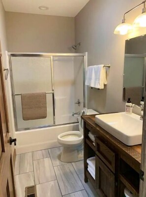 A bathroom with a shower, toilet, and sink.
