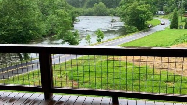 Eine Holzterrasse mit Blick auf einen Fluss und bewaldete Hügel.
