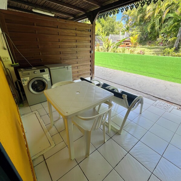 Une terrasse couverte équipée d’un lave-linge, d’une table et de chaises.