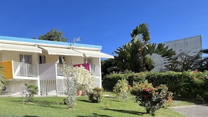 A two-story house with a blue roof, white exterior walls, and a balcony with white railings.
