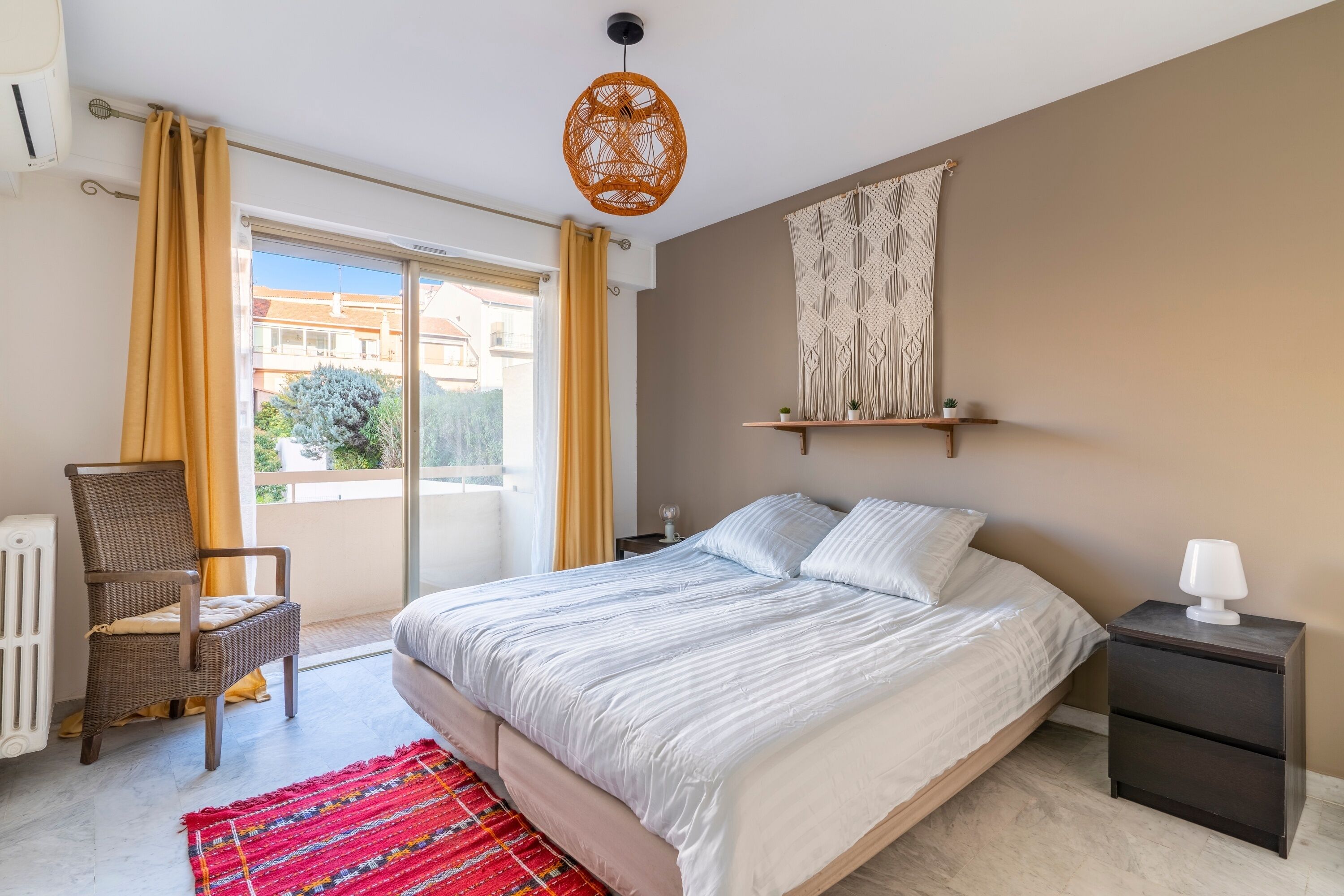 A bedroom with a bed, a chair, a nightstand, and a window with curtains.