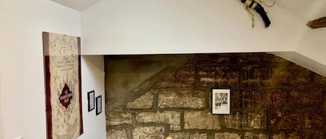 Een kamer met een stenen muur, een houten trap en een inlijsting kaart aan de wand.