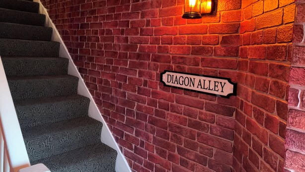 Una scala con un muro di mattoni rossi e un cartello che riporta la scritta "DIAGON ALLEY".