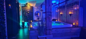 Ein Wellnessbereich mit Whirlpool, Zierpflanzen und stimmungsvoller Beleuchtung.