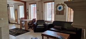 Una sala de estar con un sofá de cuero negro, una mesa de centro de madera y un comedor con mesa y sillas.