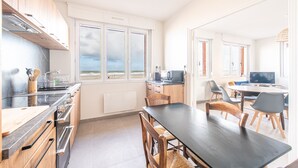 A modern kitchen with a large island, wooden cabinets, and a view of the beach. - Banc des Flandres - Appt proche plage (Bray-Dunes)