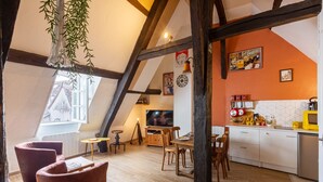 Eine gemütliche Küche mit Holzbalken, einem Essbereich mit Stühlen und einem Fernseher im Hintergrund.