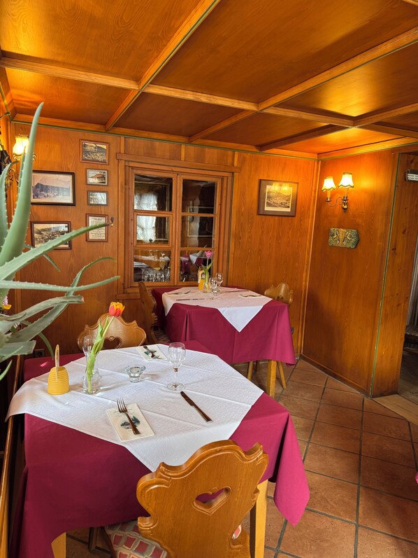 A restaurant with wooden walls, framed pictures, and tables set with white tablecloths and pink napkins. - Hotel-Restaurant Maien (Todtmoos)