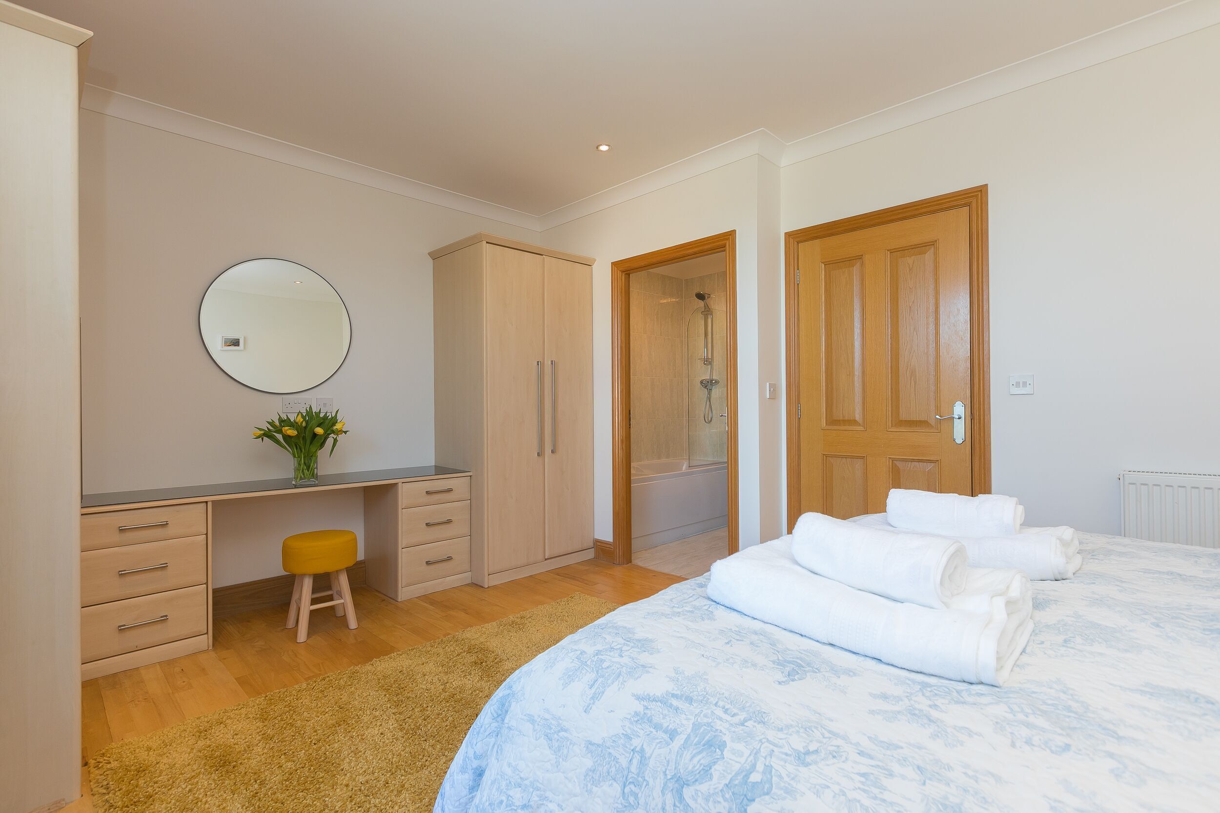 Une chambre à coucher comprenant un lit, un bureau, un miroir, une armoire et une douche.