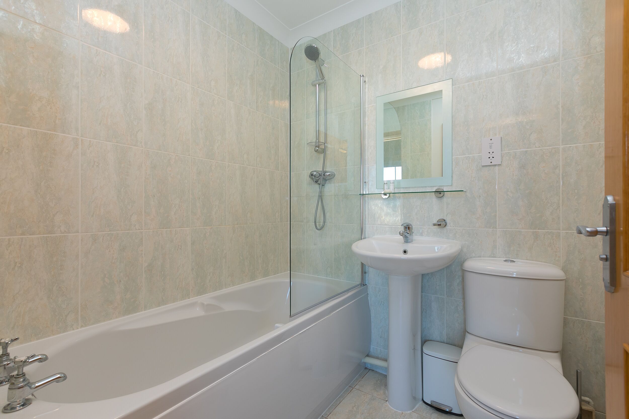 A modern bathroom with a glass-enclosed shower, a standalone sink, and a toilet.