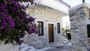 A stone building with a white facade, a wooden door, and a balcony. - Giannakis Filoxenia (Naxos)