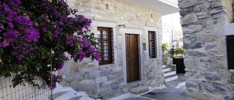 A stone building with a white facade, a wooden door, and a balcony.