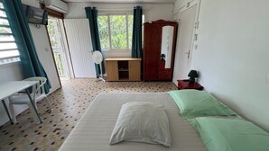 Ein Zimmer mit Bett, Schreibtisch, Kleiderschrank und Ventilator.