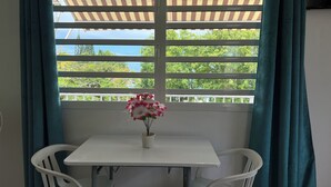 Ein kleiner Tisch mit Blumen in einer Vase, weiße Stühle und Blick durch ein Fenster mit weißer Brüstung.