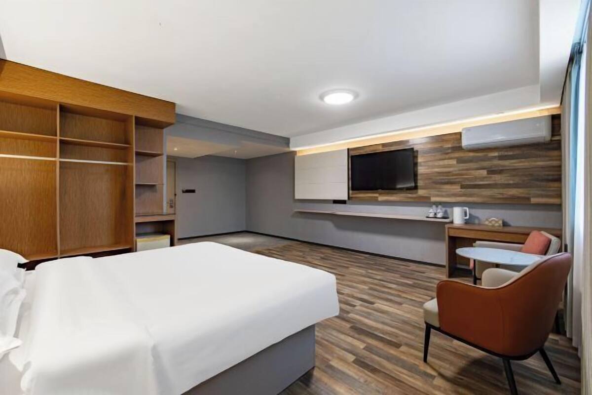 Una habitación de hotel con cama, escritorio, silla, televisor y armario.