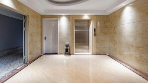 Un ascensore moderno con parete in marmo e porta che dà su un'altra stanza.