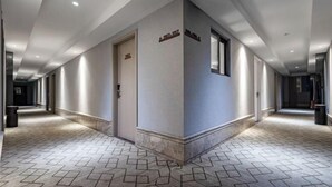 Corridoio di un hotel con pavimento a motivi geometrici, una reception e una porta con la scritta 'HOTEL'.