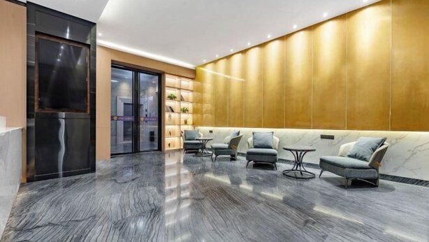 Una hall moderna con pavimento in marmo, una reception e una zona relax con sedie e divano.