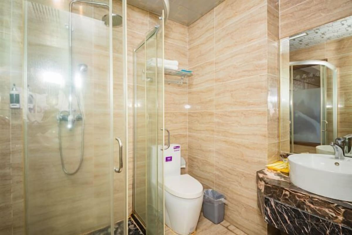 A bathroom with a glass-enclosed shower, a toilet, and a sink with a marble countertop.