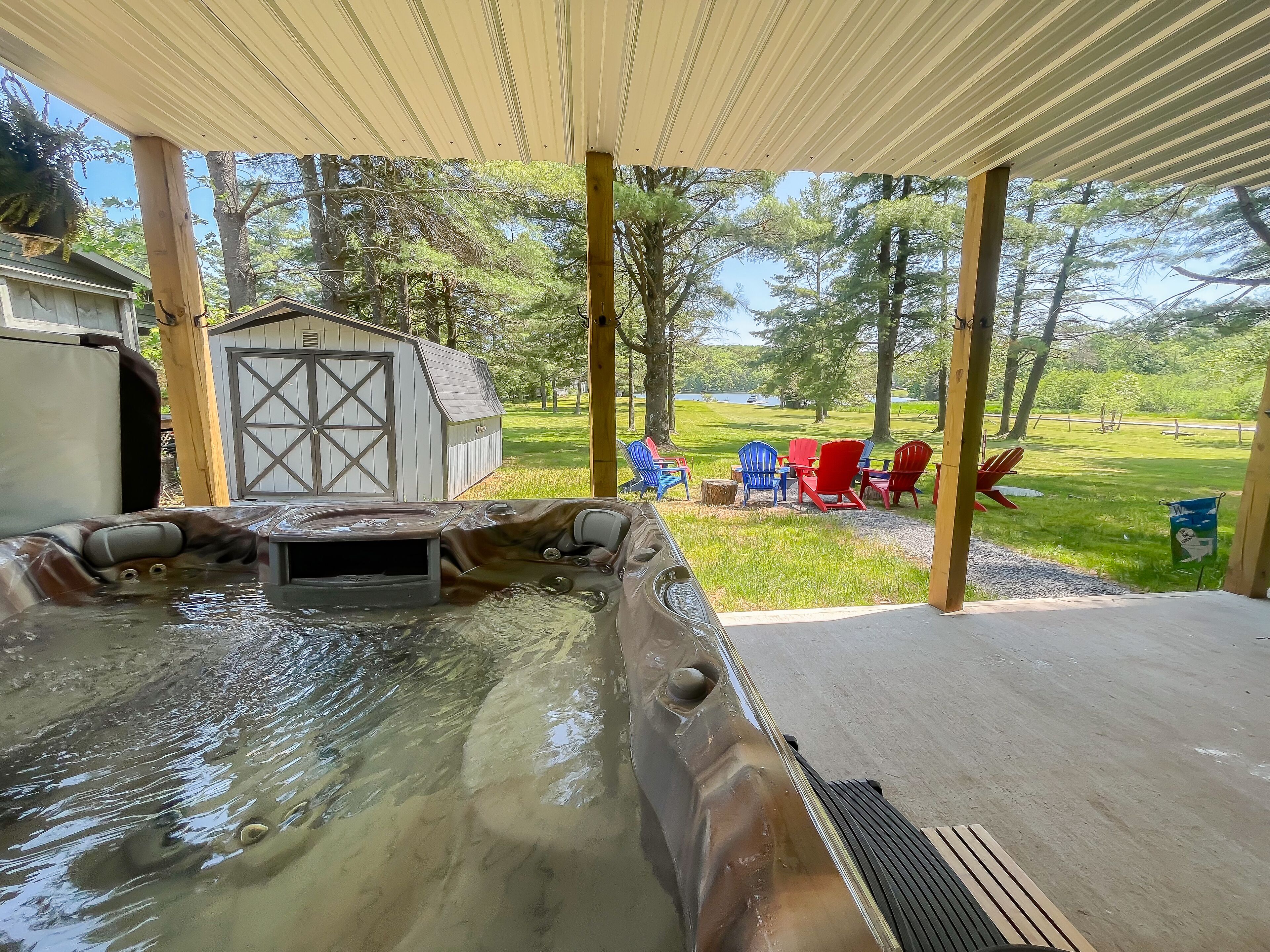 A hot tub area with a wooden deck, a shed, and outdoor seating.
