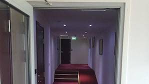 Un pasillo con alfombra roja que conduce a una puerta al final.
