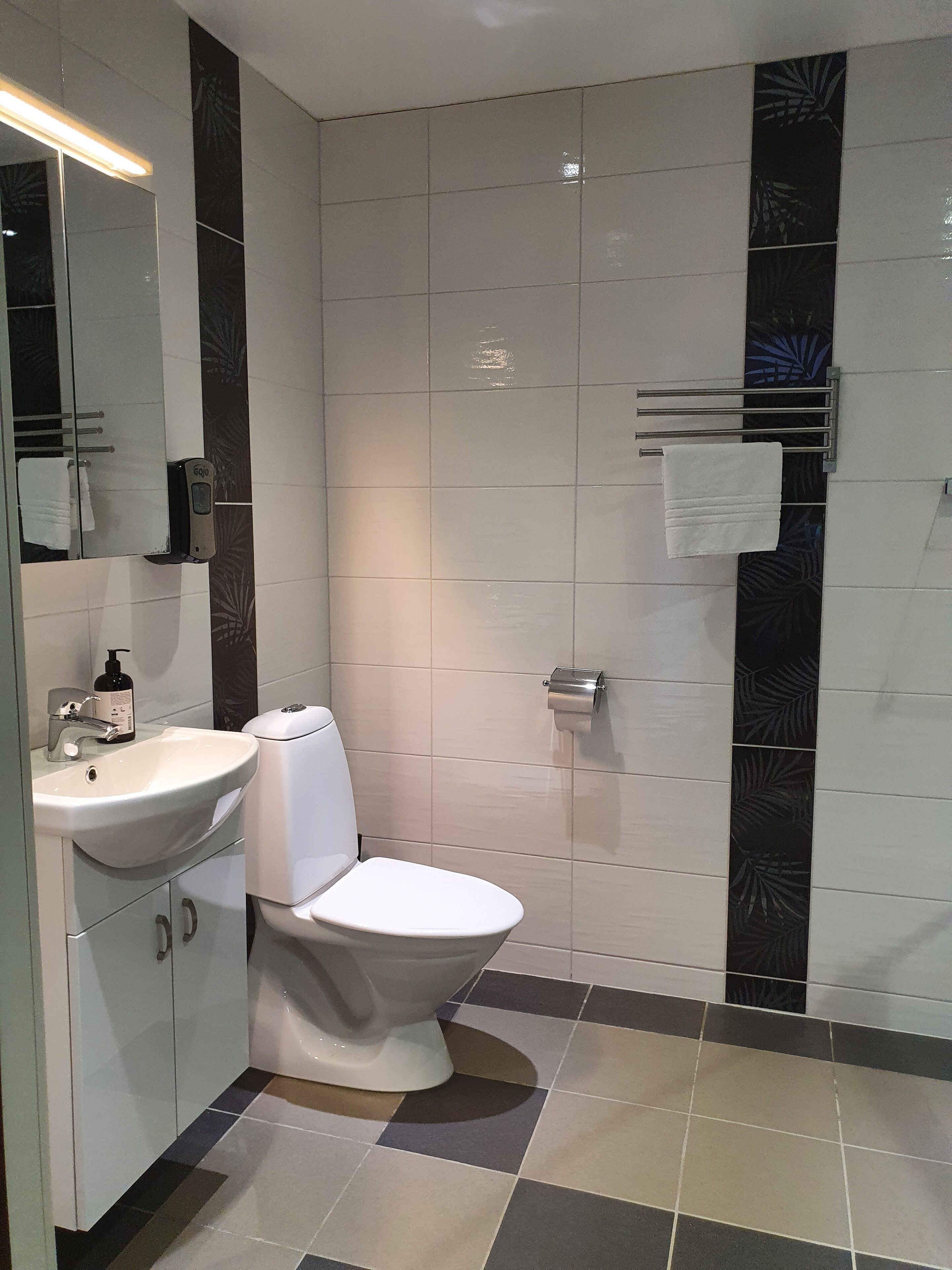Et badeværelse med en hvid vask, toilet og spejl.