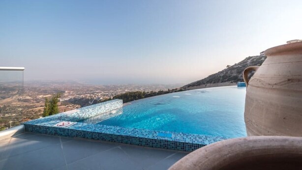 Uma piscina infinita com vista para um horizonte urbano e uma colina.