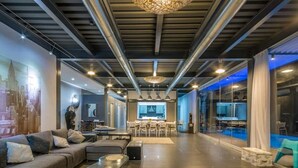 Um interior moderno com área de estar, bar e cozinha visíveis através de paredes de vidro.