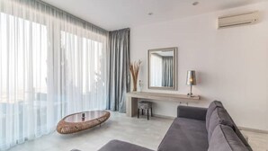 Uma sala de estar moderna com um sofá cinzento, uma mesa de centro de vime redonda e uma lareira.