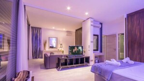 Quarto de hotel moderno com cama, televisão, escrivaninha e área de estar.