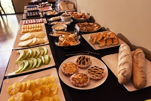 Een buffet met diverse soorten eten, zoals gebak, fruit en brood.