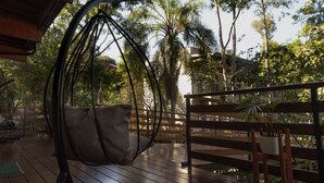 A wooden deck with a hanging chair, a bench, and a potted plant.
