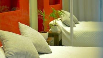 Une chambre d’hôtel avec deux lits, une plante en pot et un mur d’accent de couleur rouge.