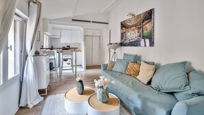 A modern living room with a light blue sofa, white decorative vases, and a painting on the wall.