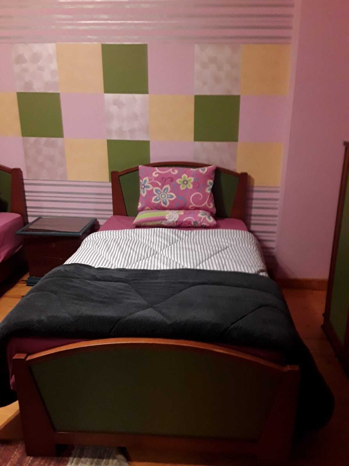 A bedroom with a bed, a nightstand, and a chair.