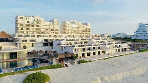 A beachfront hotel with multiple white buildings, a pool, and beach chairs. - Oceanfront 2BR Villa for 6 -  3 Bathrooms - Walk to La Isla & Beach (Cancún)