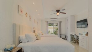 A hotel room with two beds, a desk, a TV, and a ceiling fan. - Oceanfront 2BR Villa for 6 -  3 Bathrooms - Walk to La Isla & Beach (Cancún)